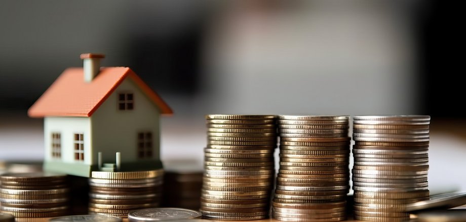 Photo of a house perched on a mound of golden coins, symbolizing