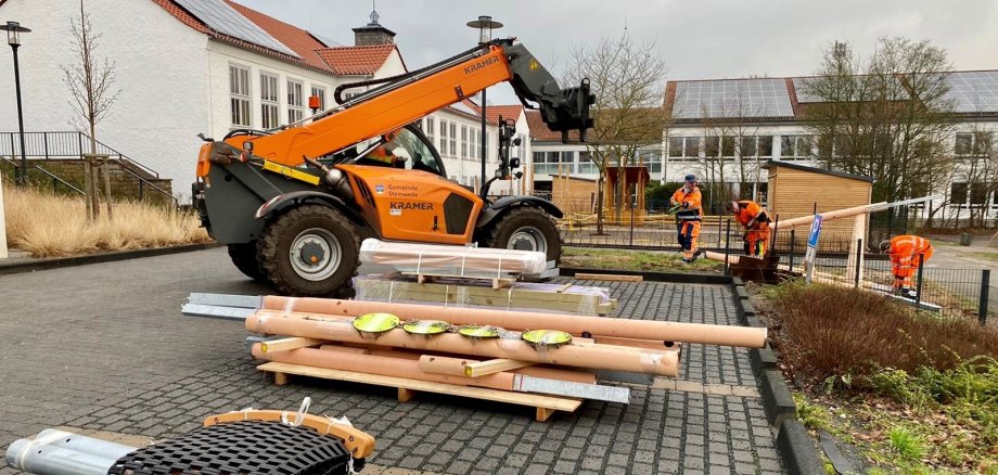 Arbeiter der Gemeinde montieren Spielgeräte, die gerade angeliefert wurden. 