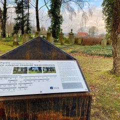 Eine Informationstafel auf einem Friedhof.