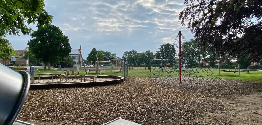 Ein Spielplatz mit verschiedenen Spielgeräten, wie Sandkasten, Rutsche und Turnstangen. 