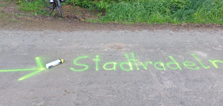 Auf einer asphaltierten Straße steht in grüner Schrift das Wort "Stadtradeln".