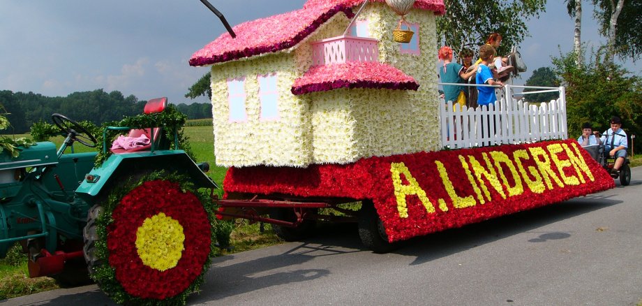 Ein mit vielen Blumen geschmückter Traktor, der bim Blumenkorso mitfährt. 