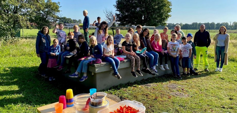 Eine Kindergartengruppe, die auf einer Wiese eines Wasserwerkes ein Picknick macht.