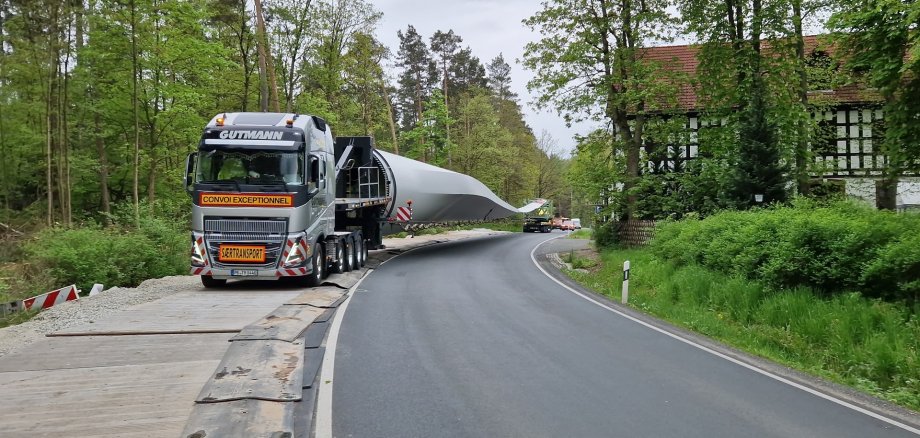 Ein Schwertransport, der ein Rotorblatt transportiert, fährt eine Bergstraße hoch. 