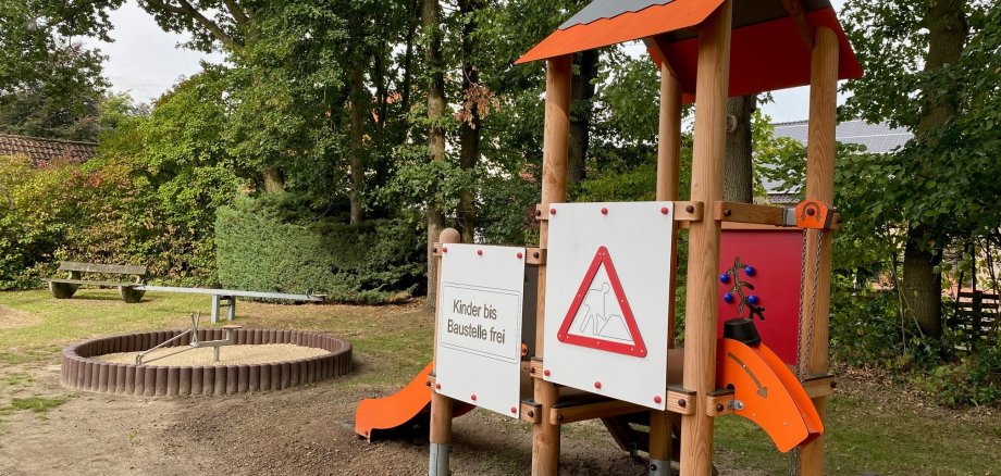 Ein Kletterturm auf einem Spielplatz. Im Hintergrund ist ein Sandkasten zu sehen.