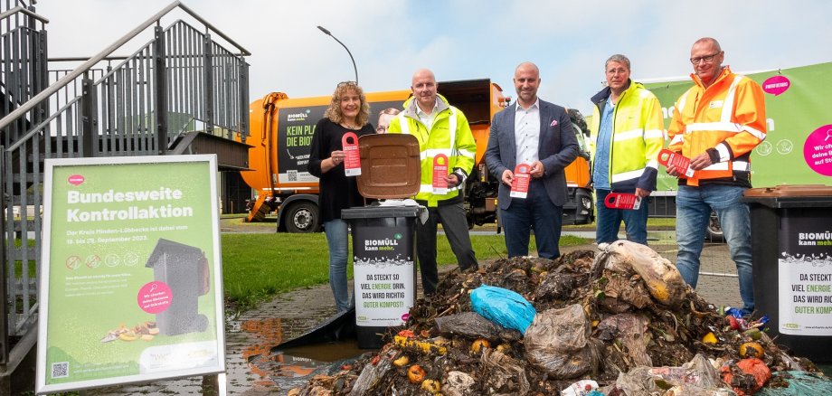 Gruppenfoto von vier Männern und einer Frau, die hinter einem Haufen Biomüll stehen, in dem viel Plastikstörstoffe zu erkennen ist.  