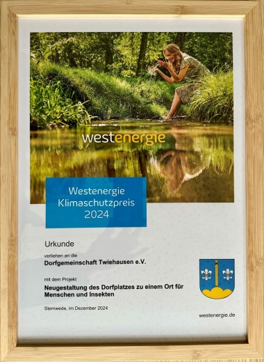 Eine Urkunde mit dem Logo des Unternehmens Westenergie, dem Wappen der Gemeinde Stemwede, einem Foto einer Naturaufnahme und der Aufschrift: Klimaschutzpreis 2024.