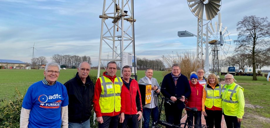 Gruppenfoto mit zehn Menschen vor einer Ladesäule. 