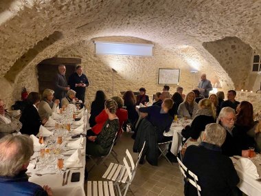 Ein festliches Essen in einem Gewölbekeller. An gedeckten Tafeln sitzen mehrere Menschen.