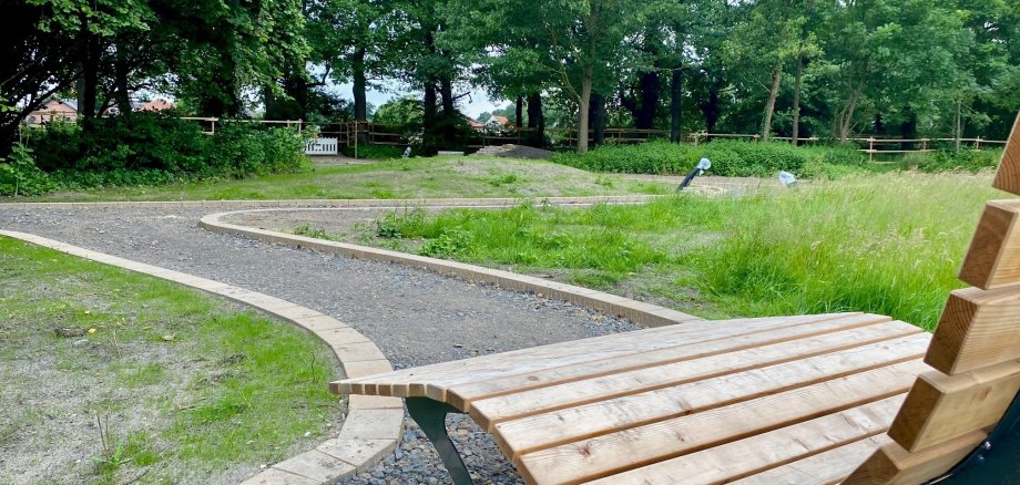 Eine Nahaufnahme einer Holzbank, die in einem Park steht, in dem gerade die Wege und Grünanlagen erneuert werden. 