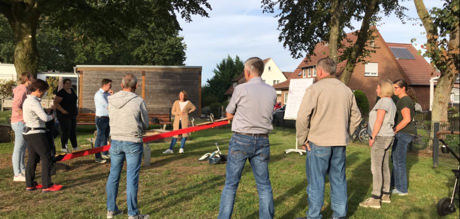 Eine Gruppe Erwachsener auf einem Spielplatz, die miteinander reden.