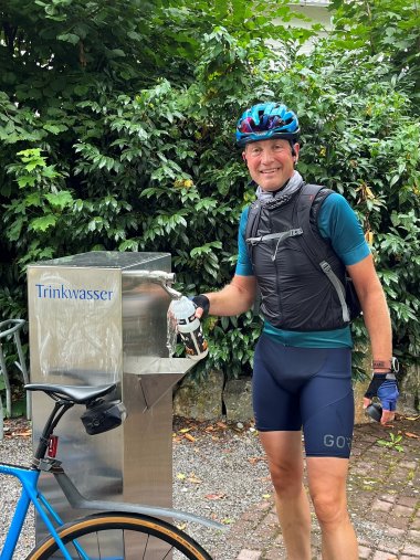 Radfahrer steht an einem Trinkwasserspender.