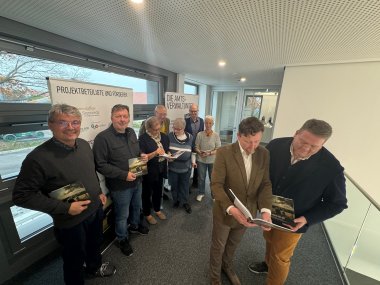 Sechs Männer und Frauen, die sich zum Gruppenfoto aufgestellt haben und jeweils ein Buch "Nachbarn wie wir" in den Händen halten.