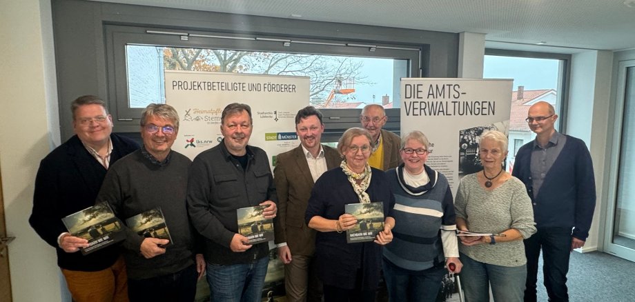 Sechs Männer und Frauen, die sich zum Gruppenfoto aufgestellt haben und jeweils ein Buch "Nachbarn wie wir" in den Händen halten.