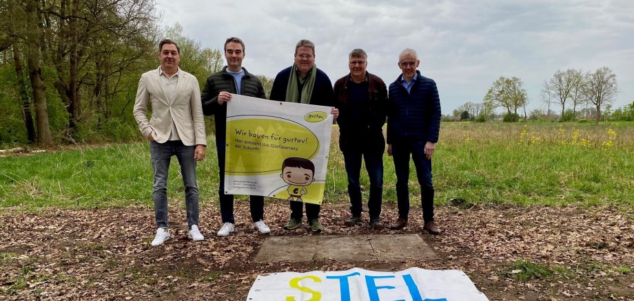 Gruppenfoto mit fünf Männern die ein Banner hoch halten, das auf den Glasfaserausbau in Stemwede hinweist.